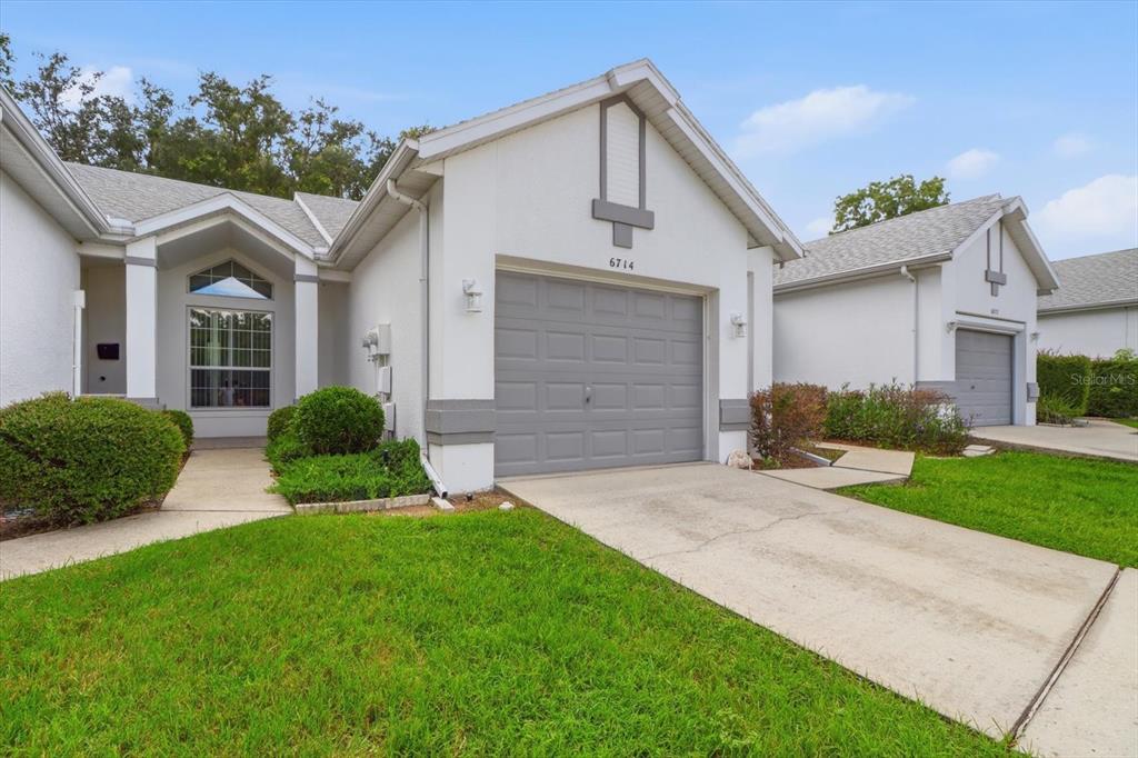 A white single-story house with a gray garage door and a concrete driveway — 6714 E WAYBRIDGE COURT, INVERNESS, FL