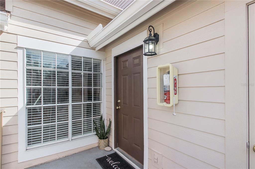 An exterior view of a residential entrance with a brown door and a fire extinguisher — 605 YOUNGSTOWN PARKWAY UNIT 30, ALTAMONTE SPRINGS, FL