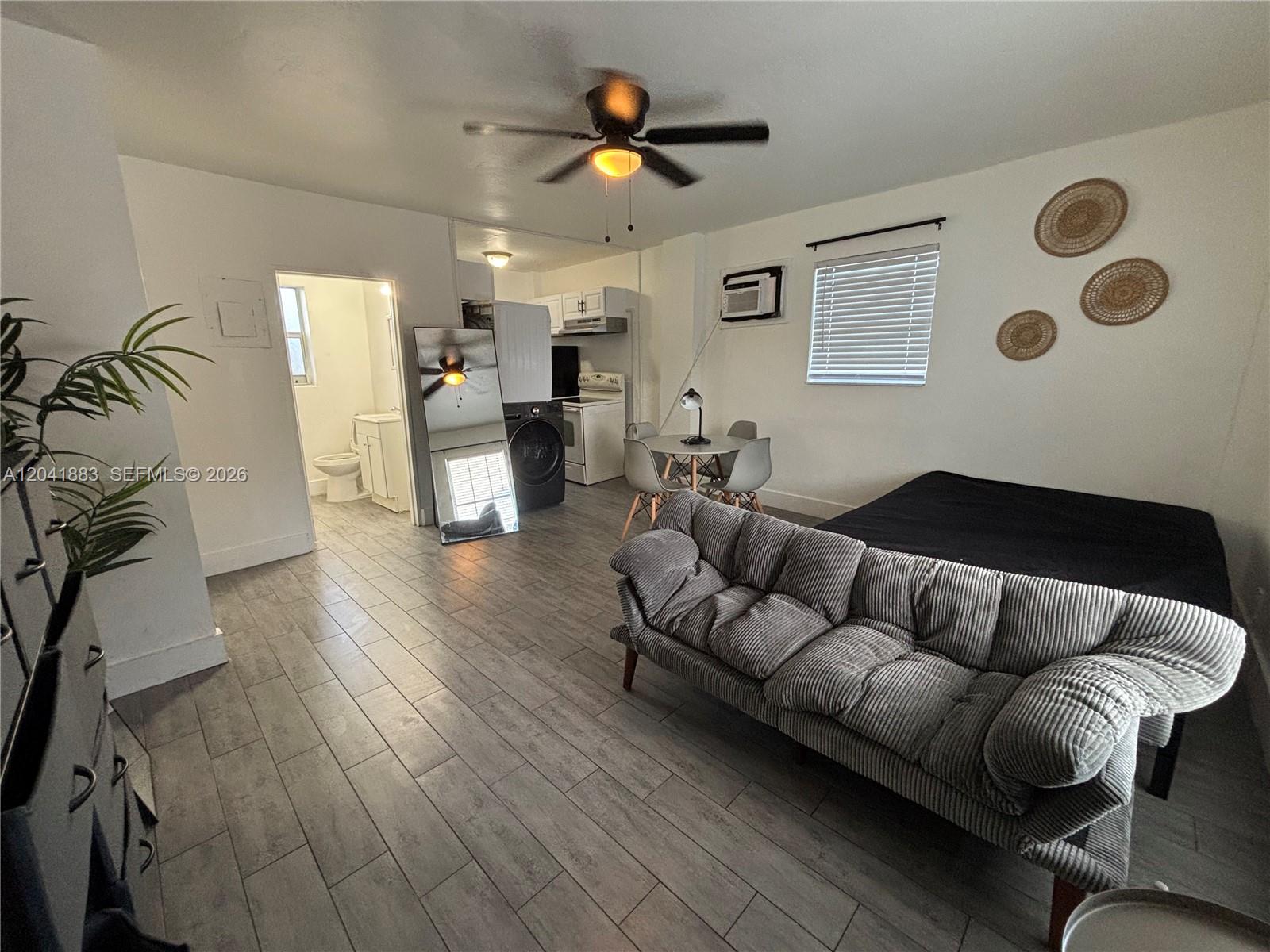 This studio apartment features a gray sofa, a bed, a small dining area, and tile flooring — 1843 Dewey St # 114, Hollywood FL 33020, HOLLYWOOD, FL