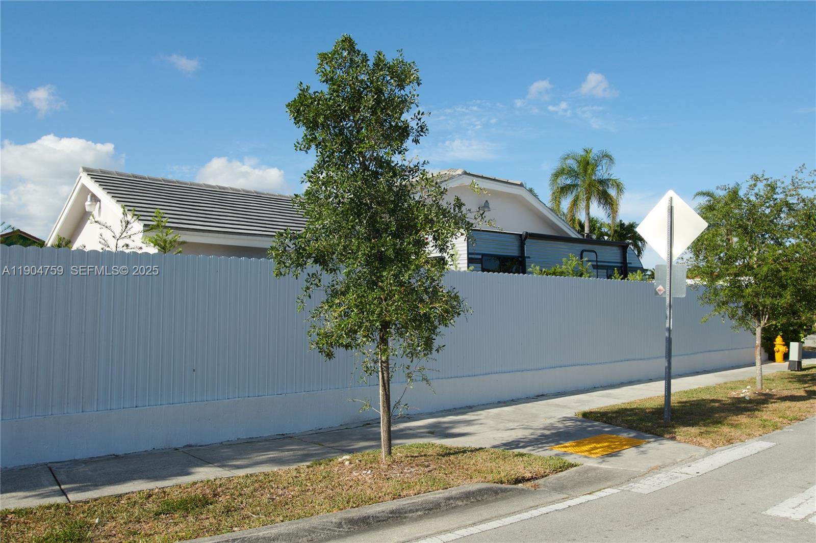 A white corrugated fence runs along a sidewalk in front of a house — 2980 SW 141st Ct, Miami FL 33175, MIAMI, FL