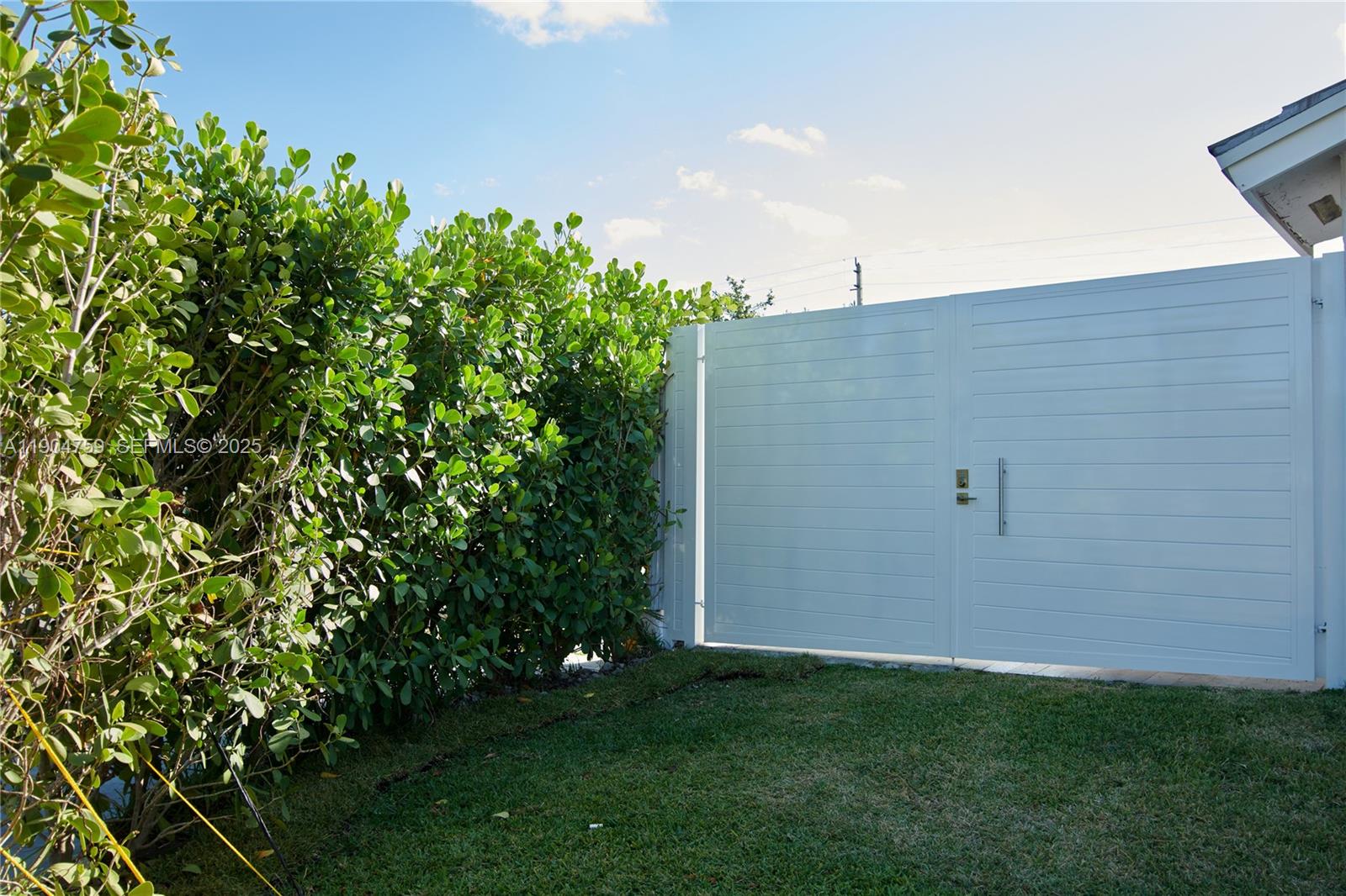 A white horizontal-slat gate stands next to a tall green hedge on a grassy lawn — 2980 SW 141st Ct, Miami FL 33175, MIAMI, FL