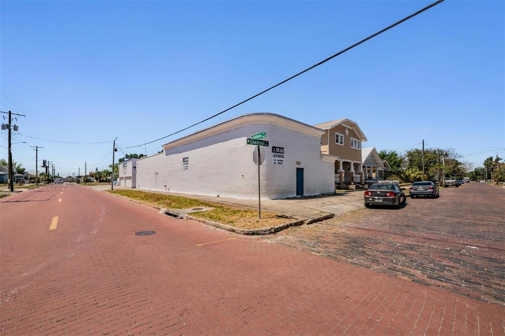 A white commercial building sits on a corner lot with brick streets — 2902 W CHESTNUT STREET, TAMPA, FL