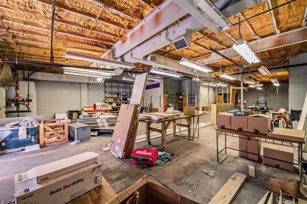 An unfinished industrial space with exposed ceiling insulation, concrete floors, and various storage boxes — 2902 W CHESTNUT STREET, TAMPA, FL
