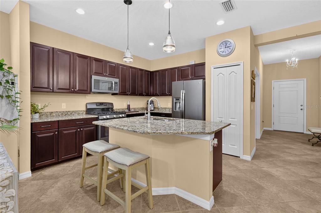 A kitchen featuring dark wood cabinets, granite countertops, a center island, and stainless steel appliances — 11417 OKALOOSA DRIVE, VENICE, FL