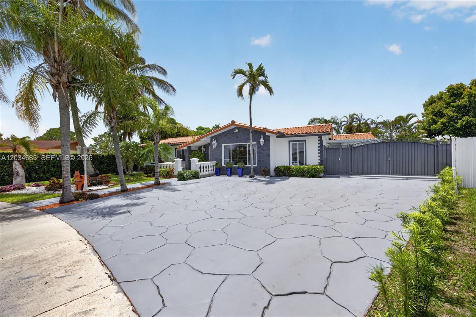 A single-story house with a gray stone-patterned driveway, palm trees, and a gated entrance — 12121 SW 107th St, Miami FL 33186, MIAMI, FL