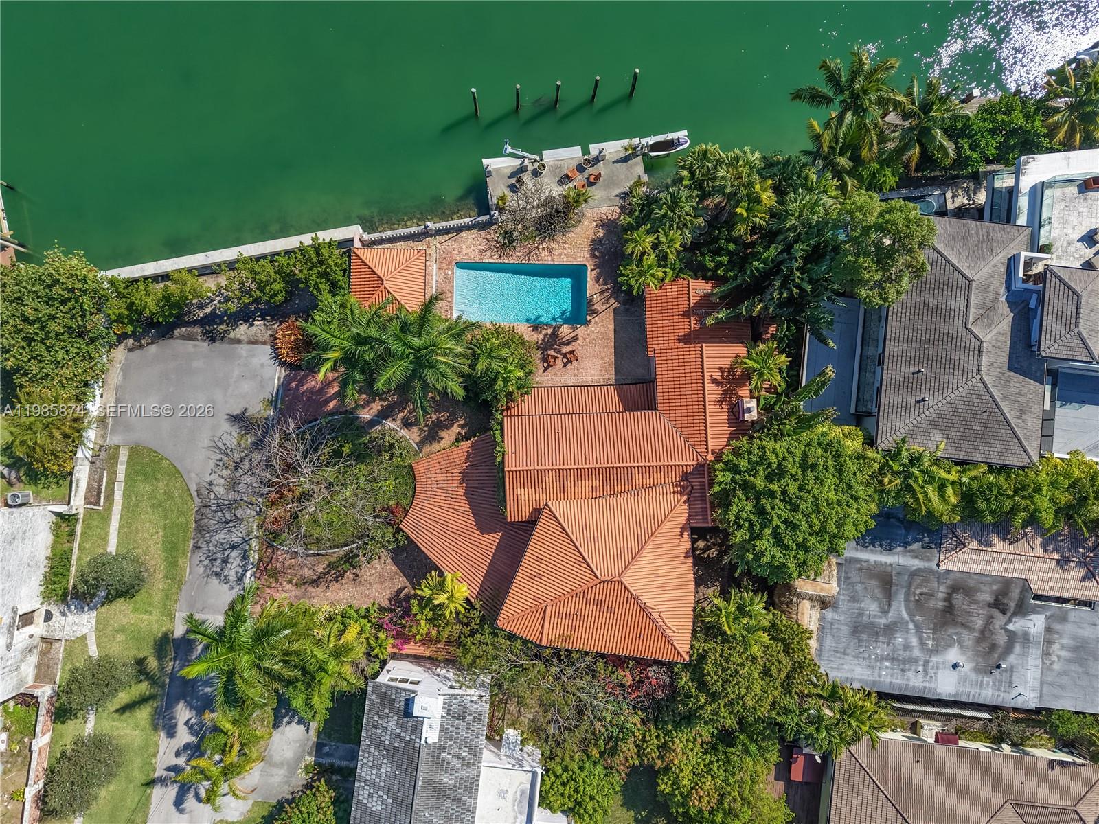 An aerial view shows a waterfront house with a tiled roof, pool, and private dock — 3310 Garden Ave, Miami Beach FL 33140, MIAMI BEACH, FL