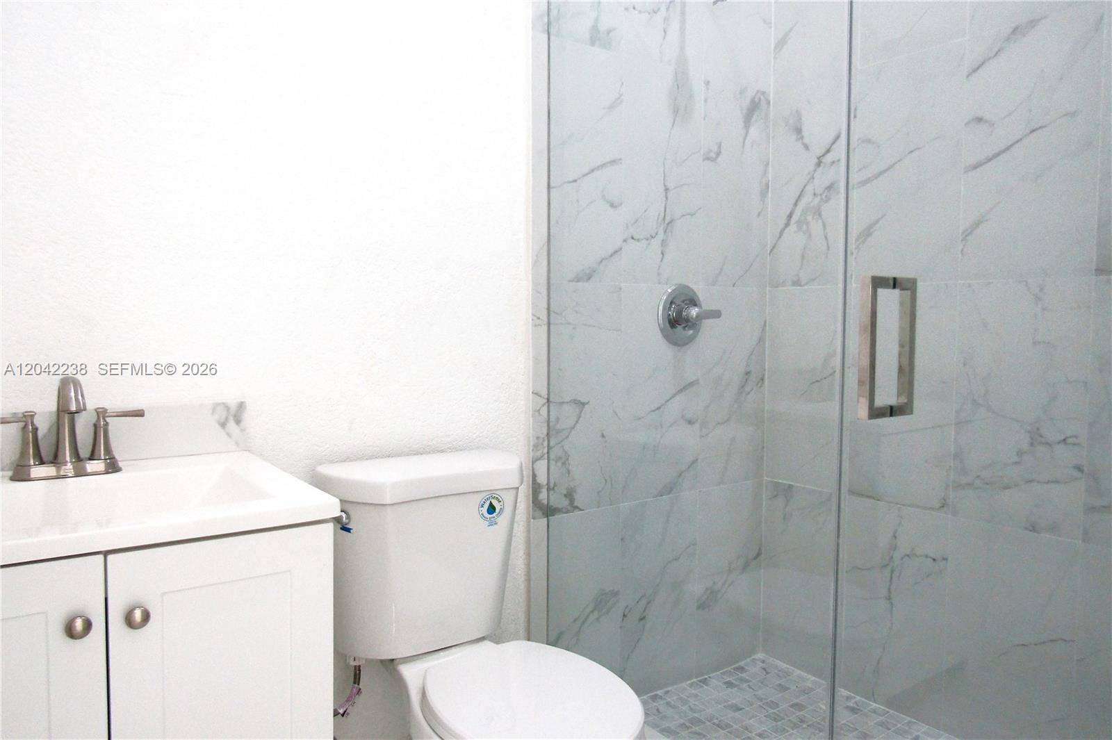 A bathroom features a white vanity, a toilet, and a glass-enclosed marble-tiled shower — 15571 SW 183rd Ln # A, Miami FL 33187, MIAMI, FL