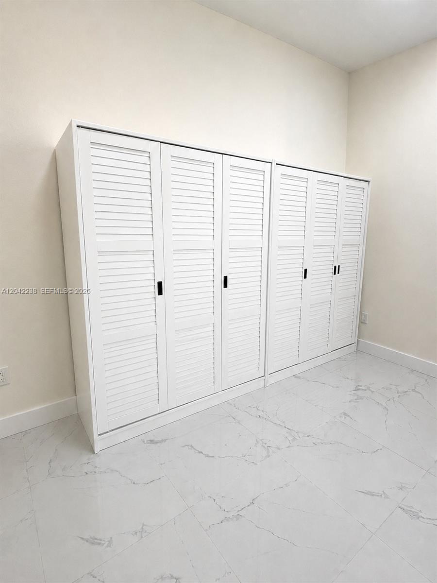 A room features white louvered-door closets against a plain wall with light-colored marble flooring — 15571 SW 183rd Ln # A, Miami FL 33187, MIAMI, FL