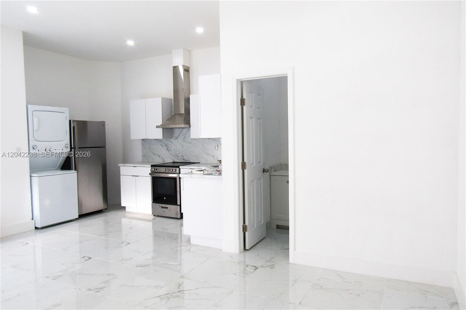 A kitchen features white cabinets, stainless steel appliances, and white marble-patterned tile flooring — 15571 SW 183rd Ln # A, Miami FL 33187, MIAMI, FL