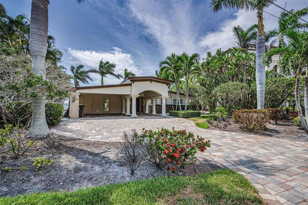 A paved driveway leads to a covered carport with white columns in front of a house — 52 N PINE CIRCLE, BELLEAIR, FL