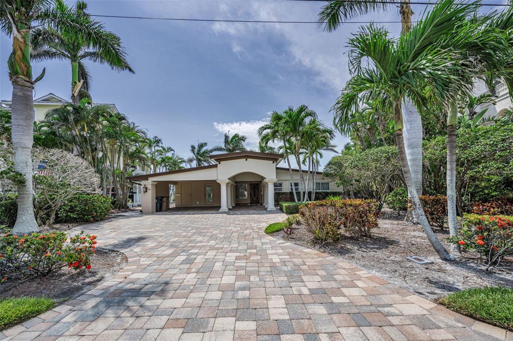 A paved driveway leads to the entrance of a single-story house with palm trees — 52 N PINE CIRCLE, BELLEAIR, FL