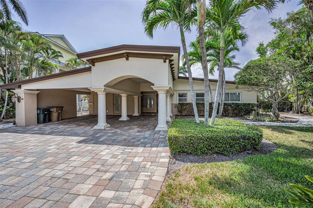 A paved driveway leads to a covered carport with white columns in front of a house — 52 N PINE CIRCLE, BELLEAIR, FL