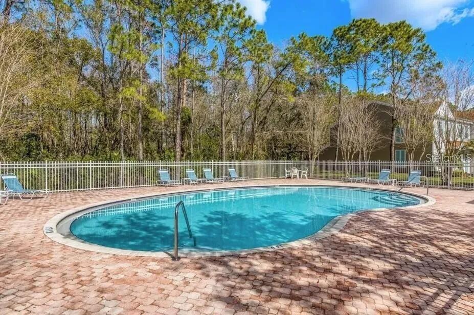 An outdoor swimming pool with a brick paver deck surrounded by a white metal fence — 8674 HUNTERS KEY CIRCLE, TAMPA, FL