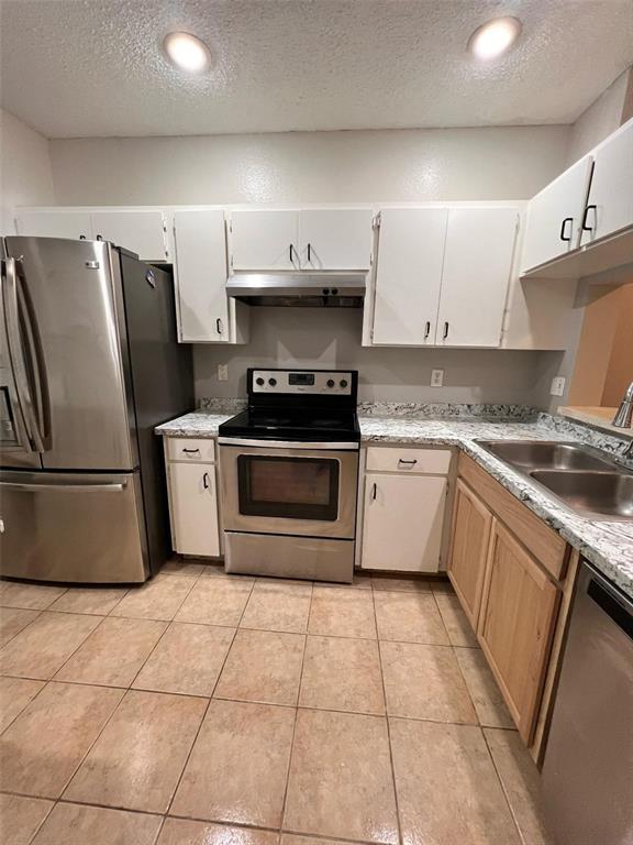 A kitchen features stainless steel appliances, white upper cabinets, wood lower cabinets, and tile flooring — 8674 HUNTERS KEY CIRCLE, TAMPA, FL