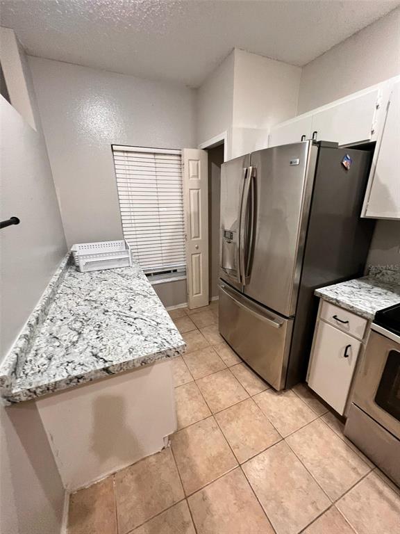 A kitchen features granite countertops, stainless steel appliances, white cabinets, and light-colored tile flooring — 8674 HUNTERS KEY CIRCLE, TAMPA, FL