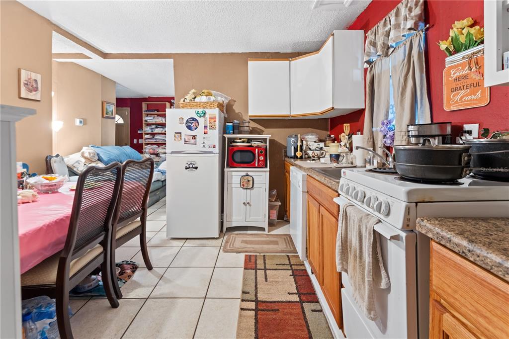 A kitchen with white cabinets, a white stove, and a dining area with a pink tablecloth — 2615 W COMANCHE AVENUE, TAMPA, FL