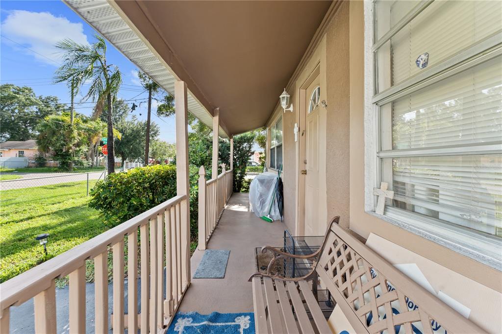 A covered front porch features a metal railing, a bench, and a view of the yard — 2615 W COMANCHE AVENUE, TAMPA, FL