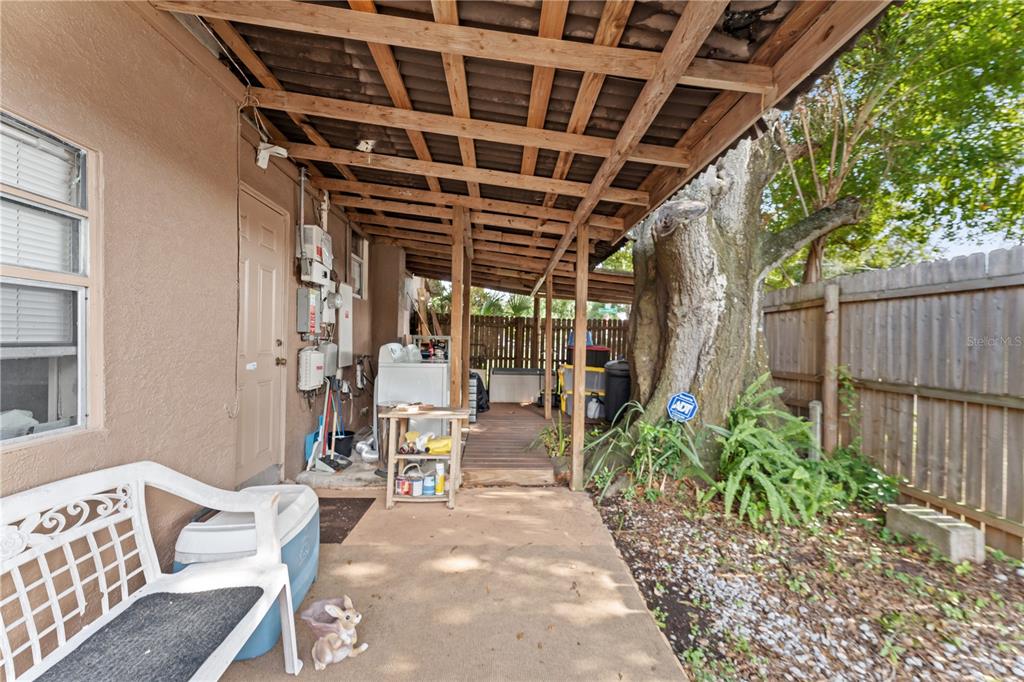 A covered patio area features a concrete floor, a wooden deck, and a large tree — 2615 W COMANCHE AVENUE, TAMPA, FL