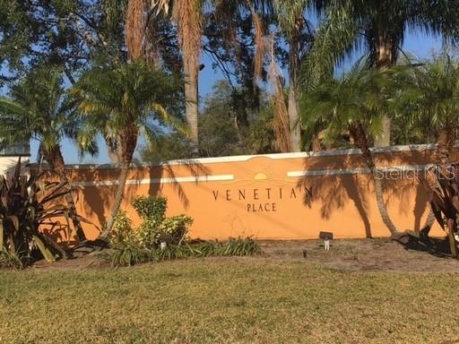 A tan stucco wall with the text "Venetian Place" stands behind palm trees and grass — 4572 COMMANDER DRIVE UNIT 1226, ORLANDO, FL