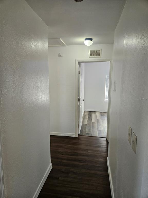 A hallway with dark wood-look flooring leads to a doorway opening into another room — 3450 17TH AVENUE S, ST PETERSBURG, FL