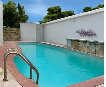 An outdoor swimming pool with a metal handrail and a stone water feature wall — 3 CLARISA STREET UNIT 447, PONCE, PR
