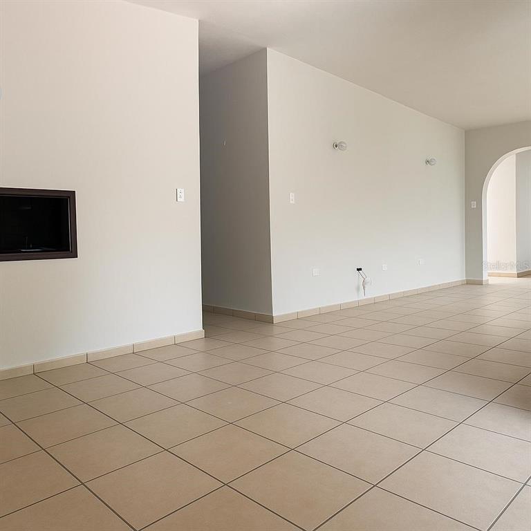 An empty room features beige tiled flooring, white walls, and a built-in fireplace — 3 CLARISA STREET UNIT 447, PONCE, PR