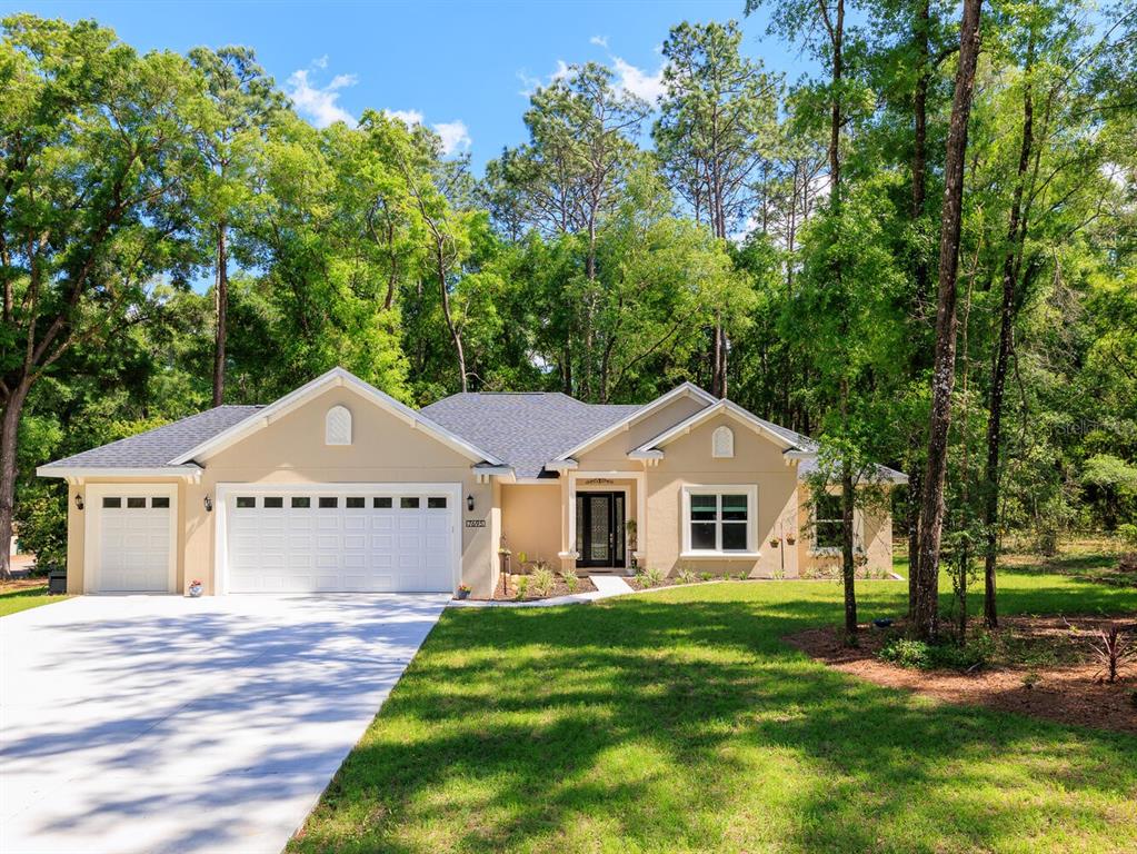 A single-story house with a beige exterior, a two-car garage, and a large front lawn — 7695 SW 188TH AVENUE, DUNNELLON, FL