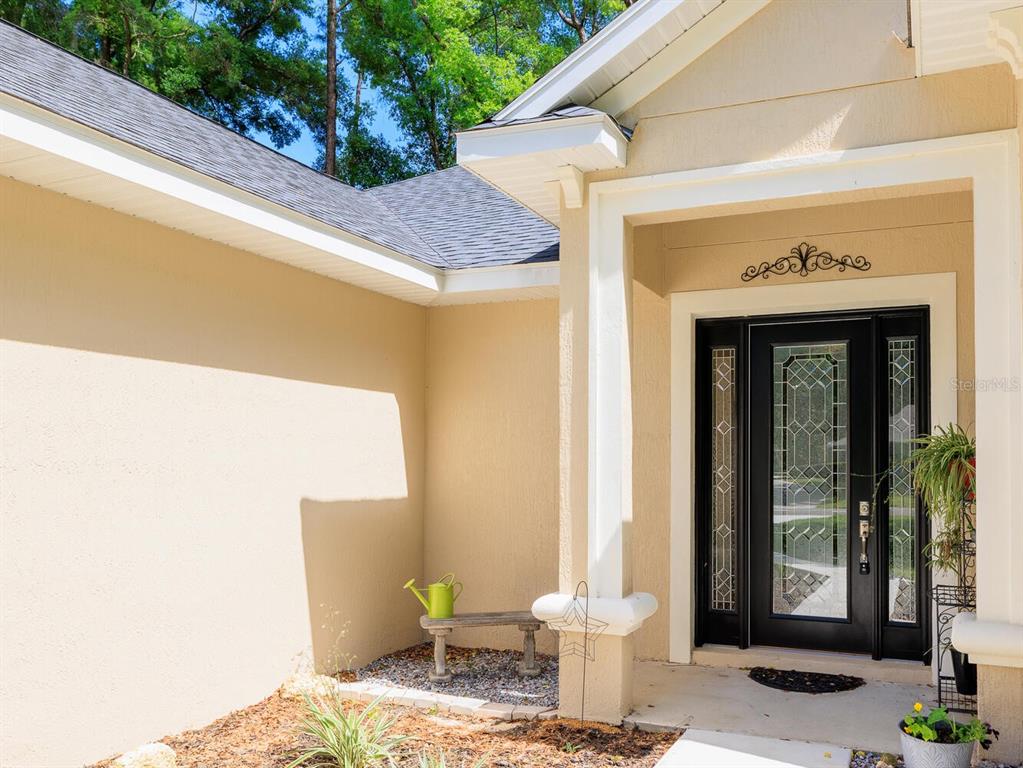 The exterior entrance features a black front door with glass panels and a small bench — 7695 SW 188TH AVENUE, DUNNELLON, FL