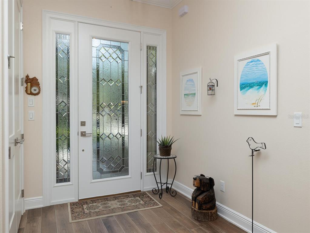 An entryway features a white front door with glass panels, wood-look flooring, and wall art — 7695 SW 188TH AVENUE, DUNNELLON, FL