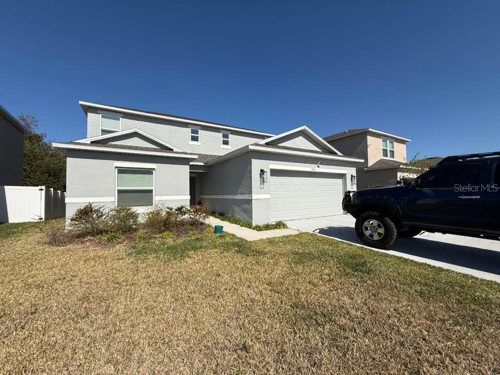 A two-story, light gray stucco house with a two-car garage and a front lawn — 3996 SOUTHERN VISTA LOOP, ST CLOUD, FL