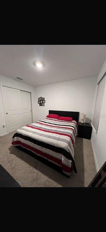 A bedroom features a bed with a striped comforter, white walls, and a closet — 3996 SOUTHERN VISTA LOOP, ST CLOUD, FL