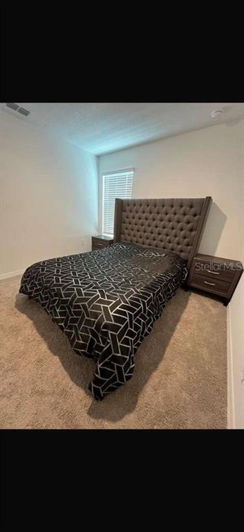 A bedroom features a tufted headboard, a patterned bedspread, and two matching wooden nightstands — 3996 SOUTHERN VISTA LOOP, ST CLOUD, FL