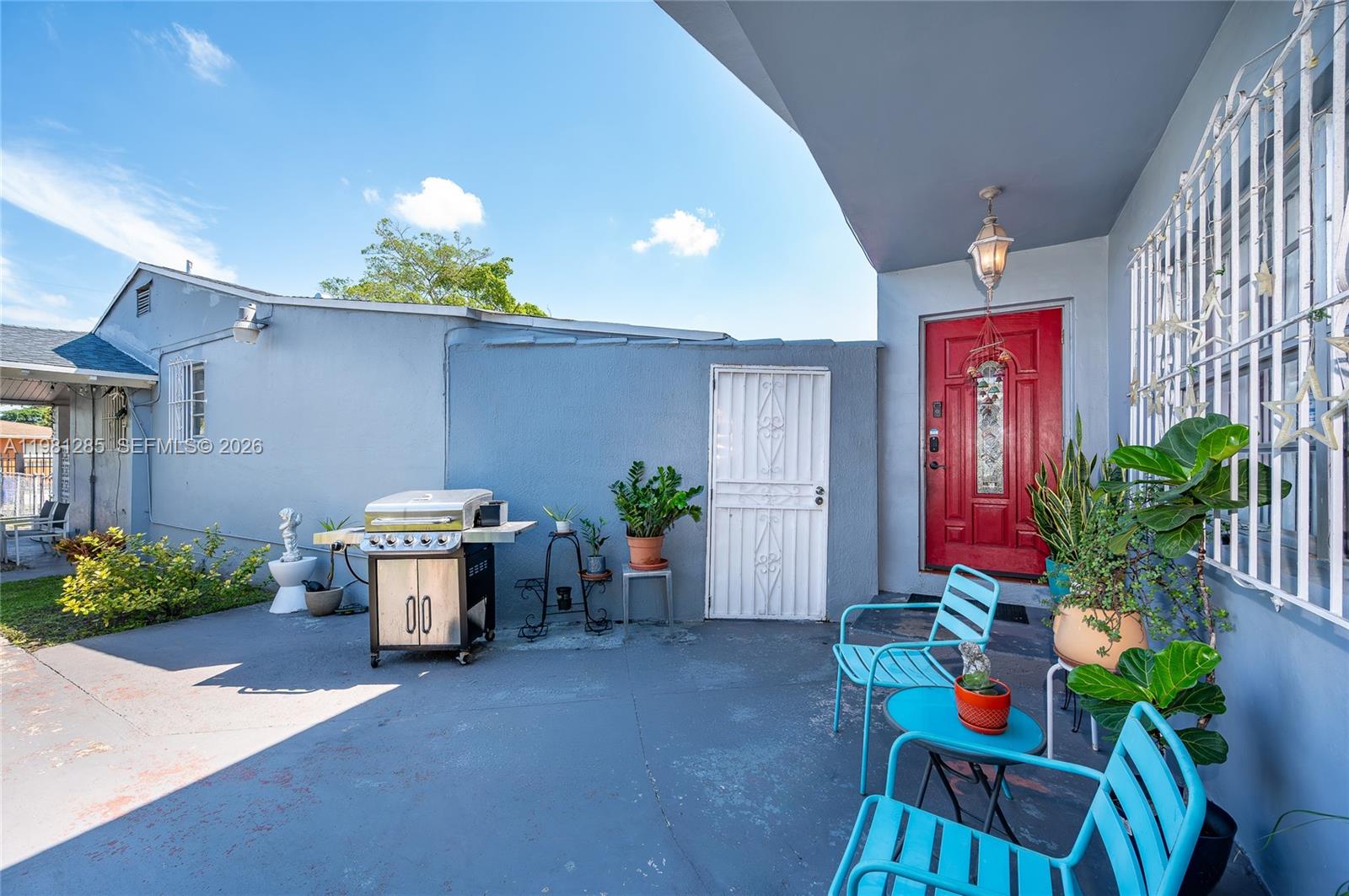 A patio features a red front door, blue metal chairs, a grill, and potted plants — 2610 NW 33rd St # 2612, Miami FL 33142, MIAMI, FL