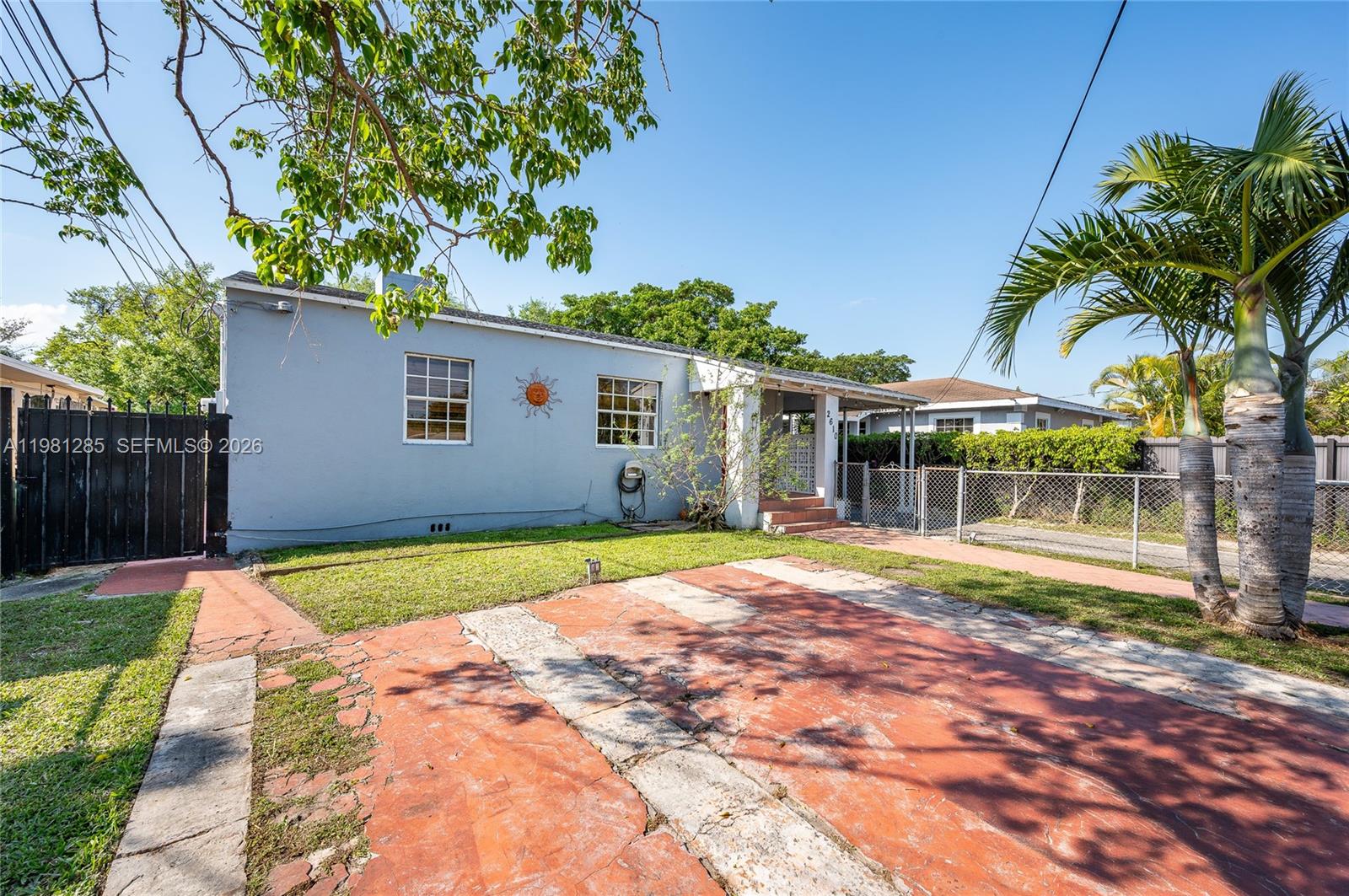 A light blue single-story house features a red paved driveway and a palm tree — 2610 NW 33rd St # 2612, Miami FL 33142, MIAMI, FL