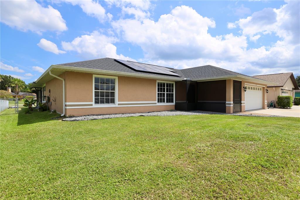 The exterior of a tan, single-story house features a dark roof with solar panels — 1123 ANNE ELISA CIRCLE, ST CLOUD, FL