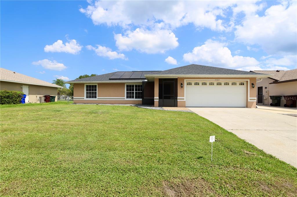 A single-story house with a tan exterior, a two-car garage, and solar panels on the roof — 1123 ANNE ELISA CIRCLE, ST CLOUD, FL