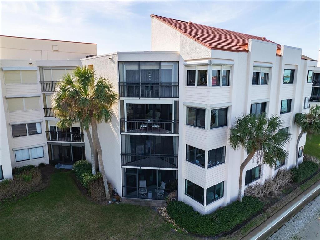 An exterior view of a multi-story residential building with screened balconies and palm trees — 5633 PUERTA DEL SOL BOULEVARD S UNIT 307, ST PETERSBURG, FL
