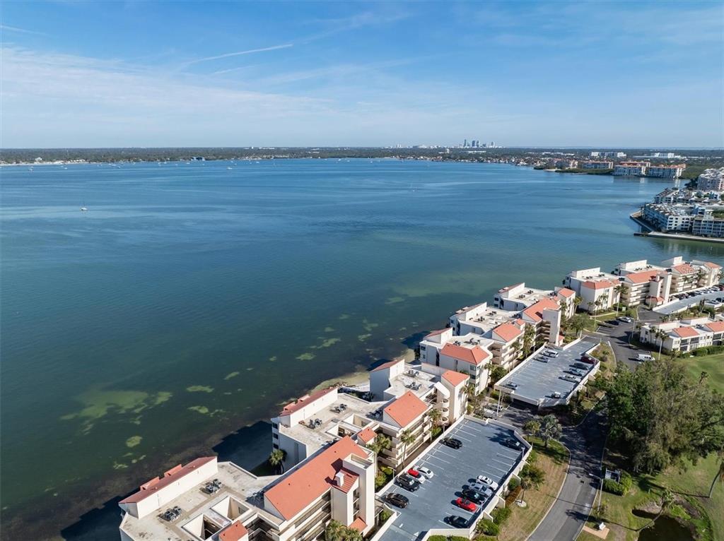 An aerial view shows waterfront condominium buildings with red roofs and adjacent parking lots — 5633 PUERTA DEL SOL BOULEVARD S UNIT 307, ST PETERSBURG, FL
