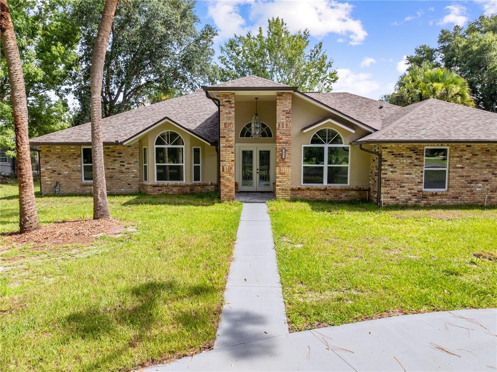 A single-story house with a brick facade, arched windows, and a central covered entryway — 2082 CAMELOT BOULEVARD, ST CLOUD, FL