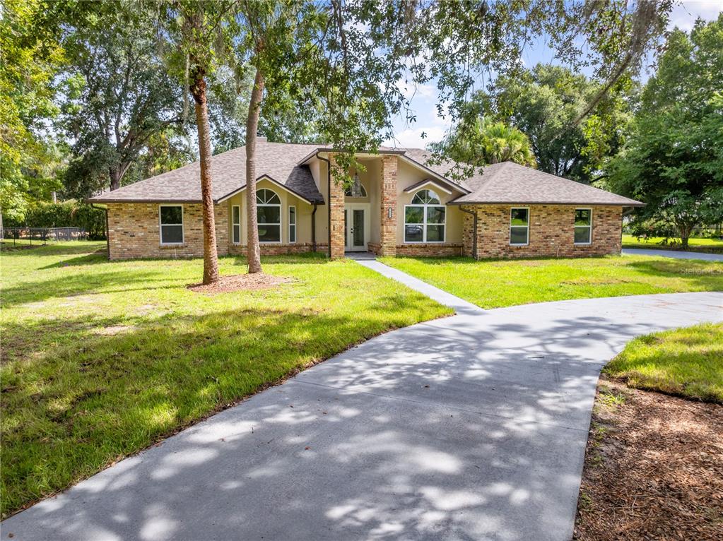 A single-story brick house with a central entryway and a curved concrete driveway — 2082 CAMELOT BOULEVARD, ST CLOUD, FL