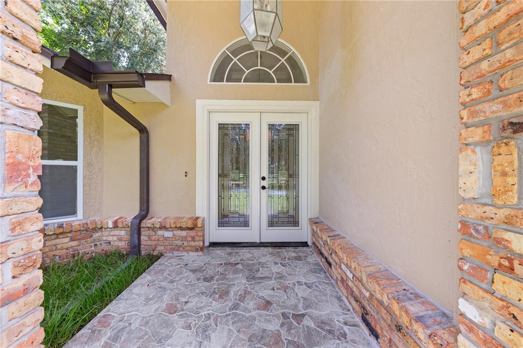A stone-paved entryway features double glass doors, a brick facade, and a semi-circular transom window — 2082 CAMELOT BOULEVARD, ST CLOUD, FL