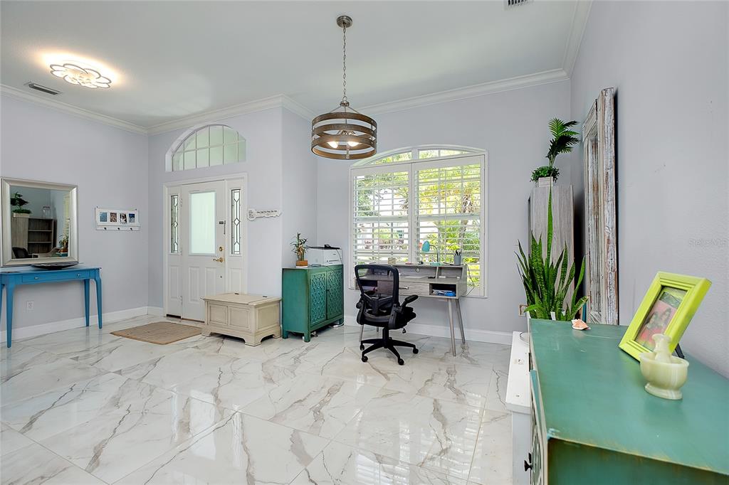 A home office with white marble-look tile flooring, a desk, and a front entryway — 360 CEDARBROOK COURT, VENICE, FL