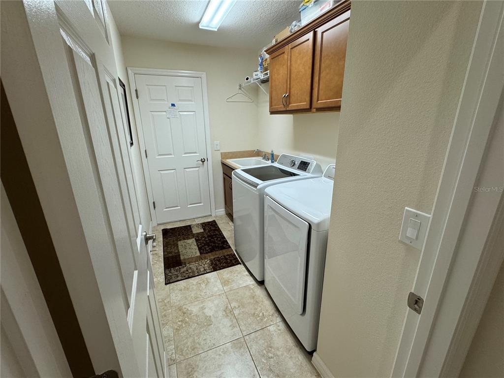 A laundry room features tile flooring, white appliances, wooden cabinets, and a utility sink — 939 KOLLER COURT, THE VILLAGES, FL