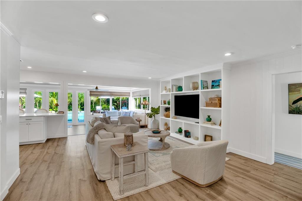 A living room features a white built-in media center, light wood floors, and patio views — VERO BEACH, FL