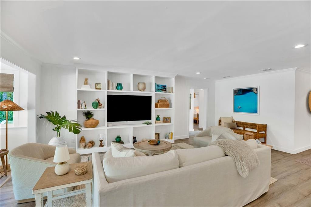 A living room features a white built-in media center, a sectional sofa, and wood flooring — VERO BEACH, FL