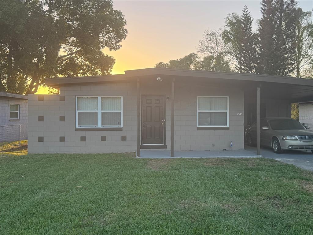 A single-story concrete block house features a front porch, a carport, and a grassy lawn — 1216 LAWNE BOULEVARD, ORLANDO, FL