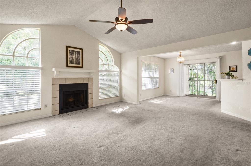 A living room with a fireplace, vaulted ceiling, ceiling fan, and carpeted flooring — 955 NORTHERN DANCER WAY UNIT 205, CASSELBERRY, FL