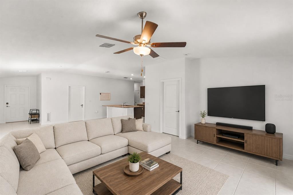 A living room features a large sectional sofa, a wooden coffee table, and a wall-mounted television — 2674 RED EGRET DRIVE, BARTOW, FL