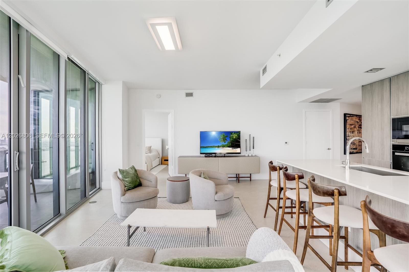 A modern open-concept living room features a kitchen island, seating area, and floor-to-ceiling windows — 2900 NE 7th Ave # 3702, Miami FL 33137, MIAMI, FL