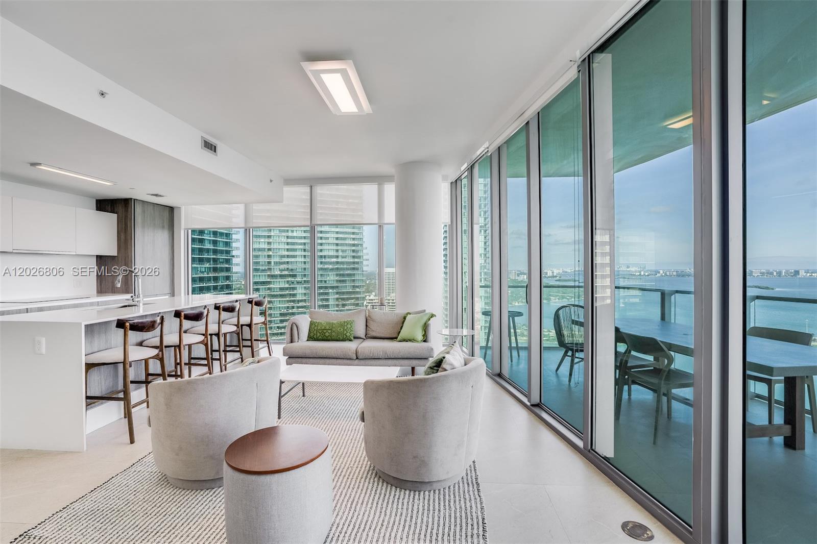 A modern living room and kitchen area features floor-to-ceiling windows with a waterfront view — 2900 NE 7th Ave # 3702, Miami FL 33137, MIAMI, FL